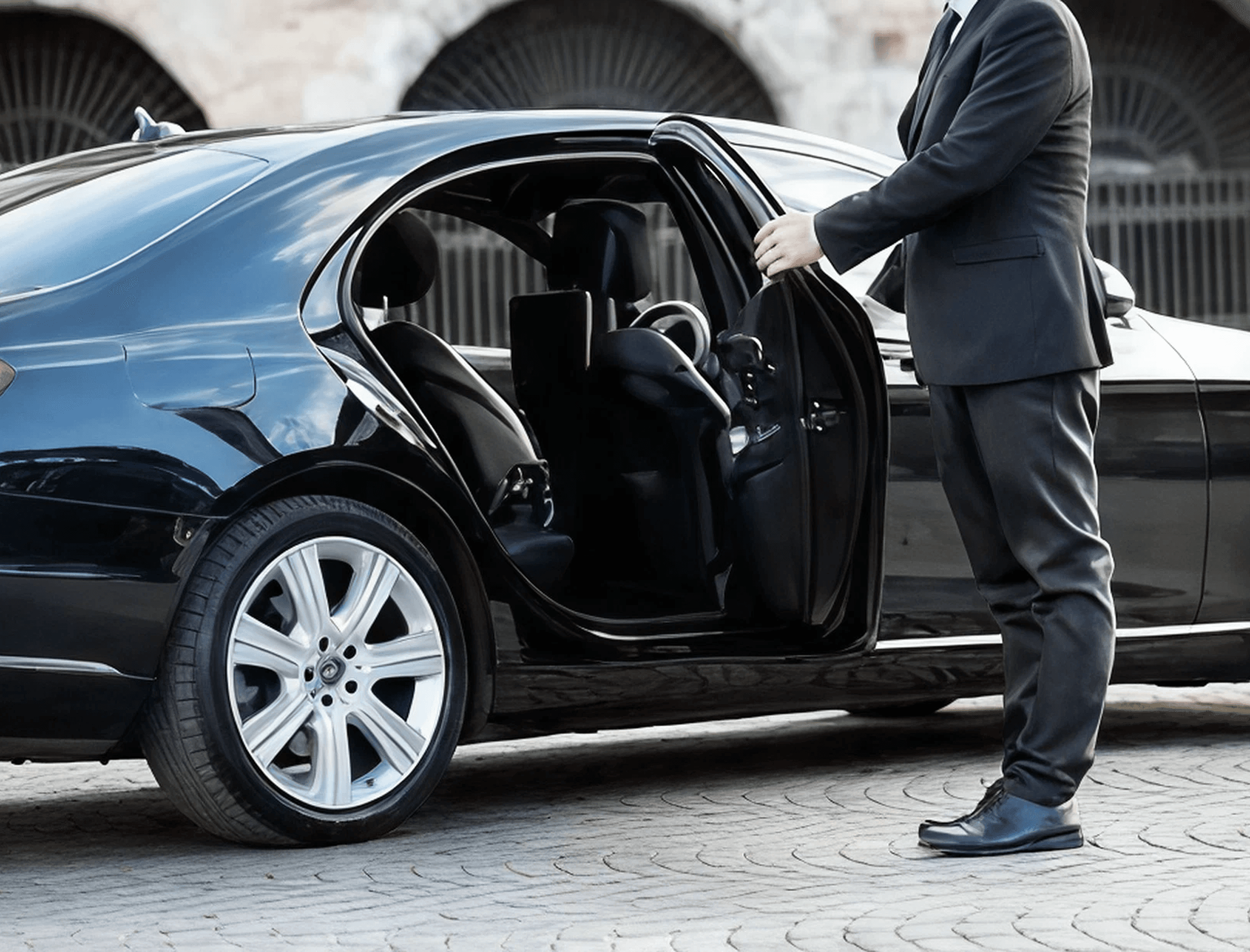Professional chauffeur opening the door of a luxury car at Birmingham Airport