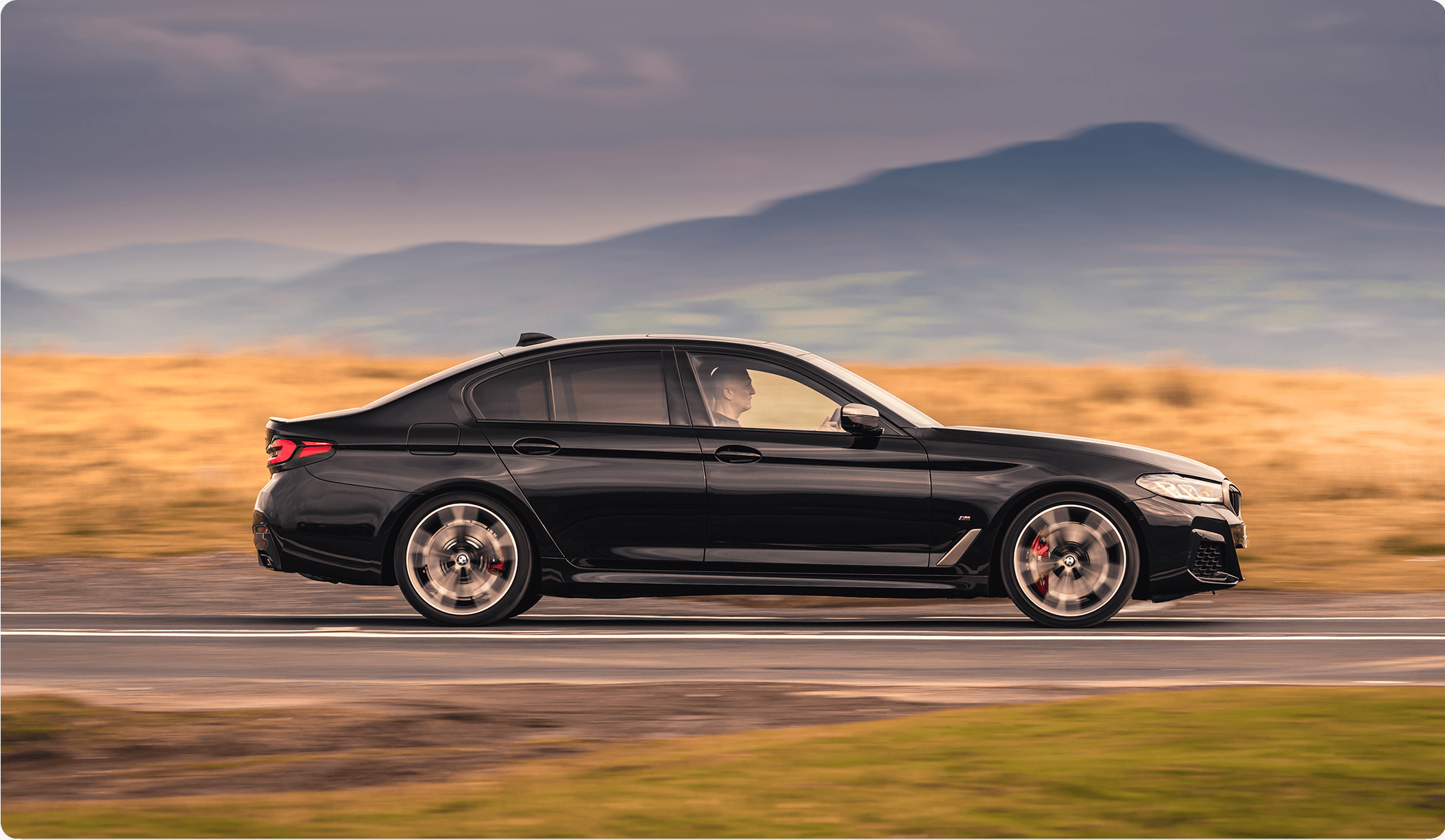 Executive chauffeur service car driving through the countryside