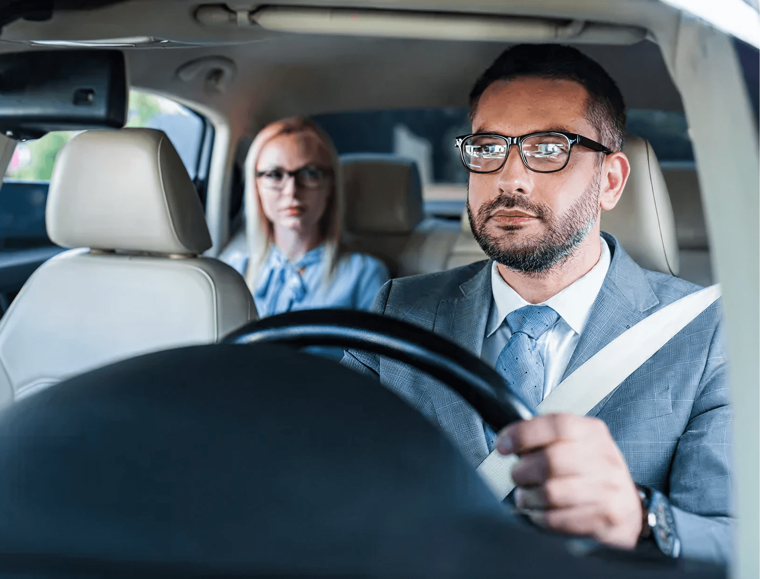 Professional chauffeur driving with a business passenger in the rear seat