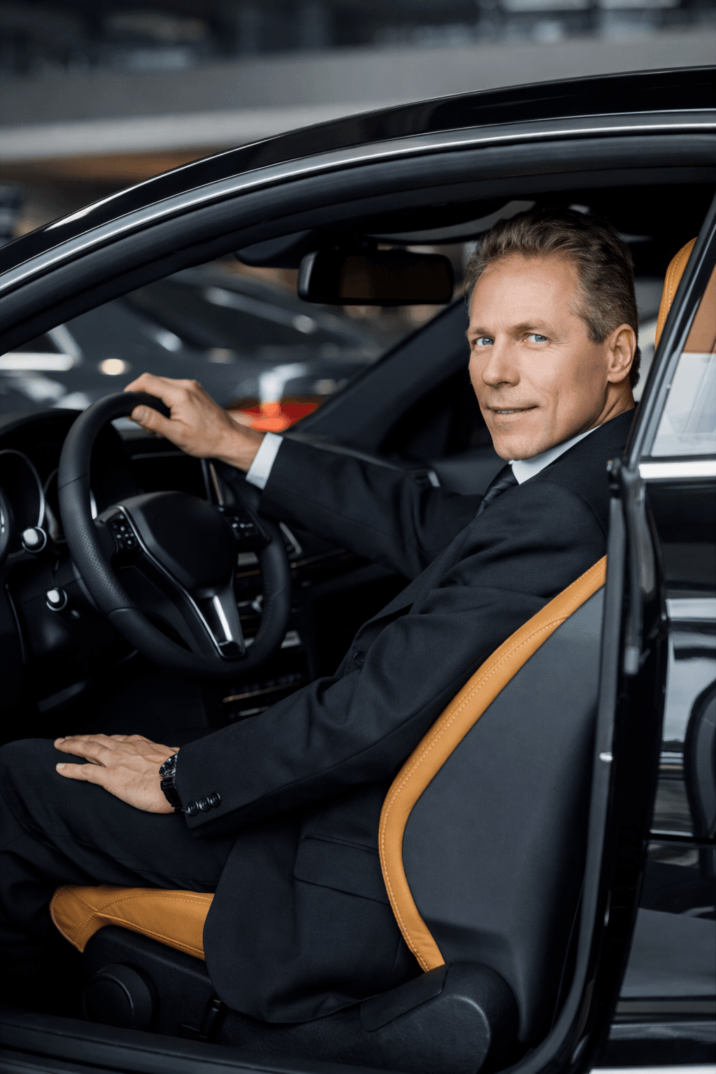 Professional chauffeur standing next to a luxury car